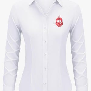 May include: A white long-sleeve button-down shirt with a red embroidered logo on the left chest. The logo features a shield with a star and the text "Alpha Kappa Alpha".
