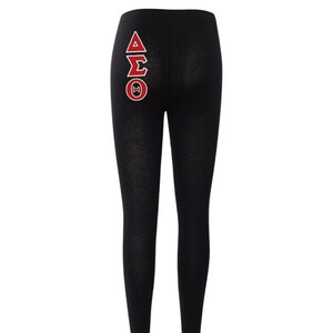 May include: Black leggings with a red and white Greek letter design on the back. The letters are Delta, Sigma, and Theta.