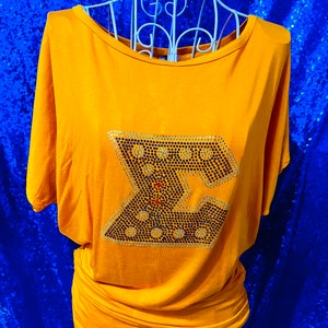 May include: A mustard yellow t-shirt with a large rhinestone letter "Z" on the front.