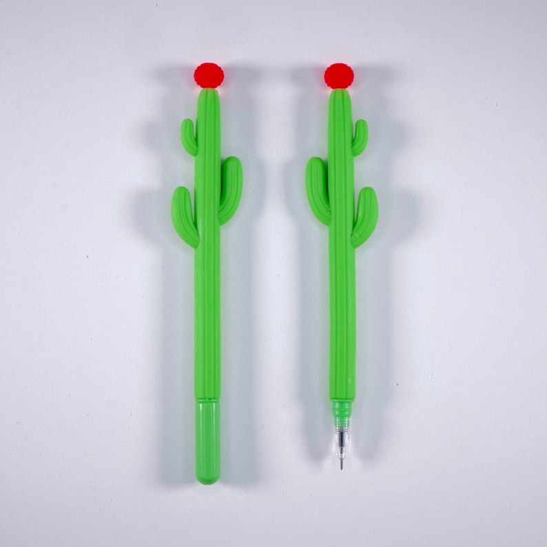 May include: Two green cactus-shaped pens with red flower tops. The pens are on a white background.