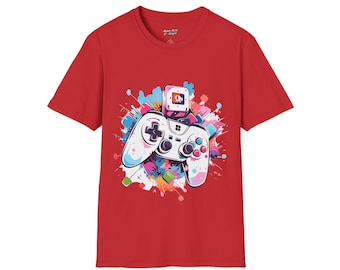 May include: Red t-shirt with a vibrant graphic of a video game controller. The controller is white with blue and pink details, set against a backdrop of colourful paint splatters. The shirt is made of a soft material.
