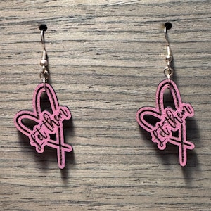 May include: Pink wooden earrings with a heart shape and the text "Let them" written inside the heart.