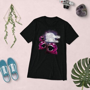 Könnte beinhalten: Schwarzes T-Shirt mit einem Motiv von drei pinkfarbenen, offenmündigen Figuren, die vor einem Vollmond in einem sternenklaren Himmel singen.