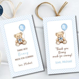 May include: Two blue and white checkered thank you tags with a teddy bear holding a blue balloon with the number one on it. The text on the tags reads "Thank you Beary much for coming! love, Michael".