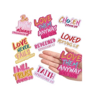 May include: A collection of colorful embroidered patches with inspirational phrases like "Love Them Anyway" and "Be Joyful Always." The patches feature various fonts and colors, with scripture references. The patches are on a white background.