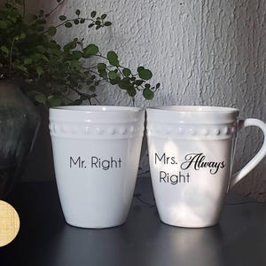 Può includere: Due tazze in ceramica bianca con scritte nere. La tazza a sinistra dice "Mr. Right". La tazza a destra dice "Mrs. Always Right".