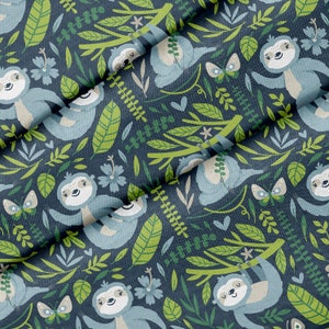 May include: A dark blue fabric with a repeating pattern of sloths hanging from branches. The sloths are light blue and have brown eyes and noses. The branches are green and there are green leaves and flowers throughout the pattern.