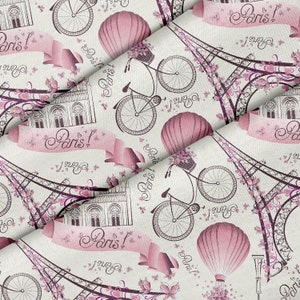 May include: A patterned fabric featuring Parisian motifs. The design includes the Eiffel Tower, bicycles with flower baskets, hot air balloons, and the text "Paris!" in a script font, in pink and brown hues on a cream-colored backdrop.