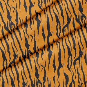 May include: Close-up of a fabric with a tiger stripe pattern. The fabric is orange with black stripes.