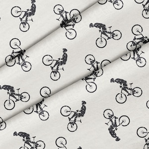 May include: A white fabric with a repeating pattern of black silhouettes of people riding bicycles. The bicycles are in various positions, some with the front wheel in the air.