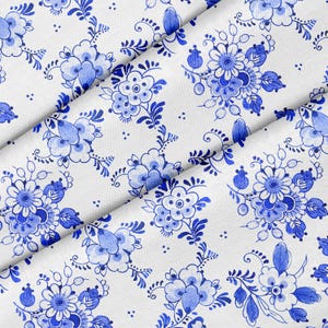 May include: White fabric with a repeating pattern of blue flowers and leaves. The fabric is folded diagonally.