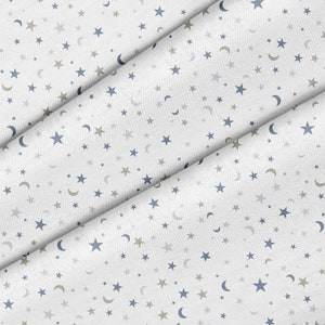 May include: White fabric with a repeating pattern of small blue stars and crescent moons, and smaller gold stars.