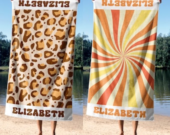 May include: Two beach towels with the name "ELIZABETH" printed on them. The towel on the left has a brown and tan leopard print. The towel on the right has a yellow, orange, and red swirl pattern.