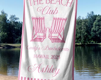 Puede incluir: Toalla de playa blanca con bordes y detalles a rayas rosas. La toalla presenta el texto "THE BEACH Club" y "Emily's Bachelorette HAWAII, 2025 Ashley" en escritura rosa. También se representan dos sillas de playa rosas.