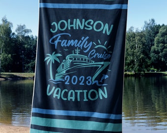 May include: A blue and black striped beach towel with the text "JOHNSON Family Cruise 2023 VACATION" and a graphic of a cruise ship, palm trees, and a sun.