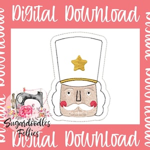 Könnte beinhalten: Ein digitales Stickmuster eines Nussknackers mit einem weißen Hut, einem goldenen Stern und einem braunen Bart. Das Muster ist schwarz umrandet und bereit zum Sticken.