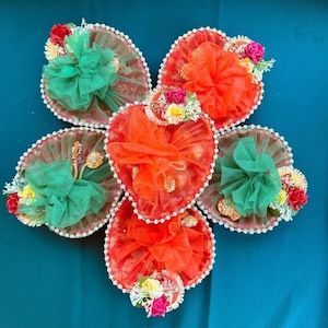 May include: Six heart-shaped decorative boxes with red and green fabric and floral embellishments. The boxes are arranged in a circle with the points of the hearts facing outward.