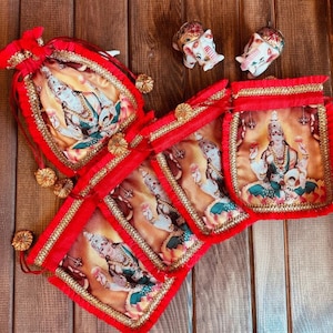 K&ouml;nnte beinhalten: Satz mit sechs roten Samt-Zugbeuteln mit goldenen Verzierungen. Jeder Beutel zeigt ein gedrucktes Bild einer hinduistischen Gottheit, Lakshmi, in sitzender Pose. Die Beutel sind mit goldenen Quasten verziert.
