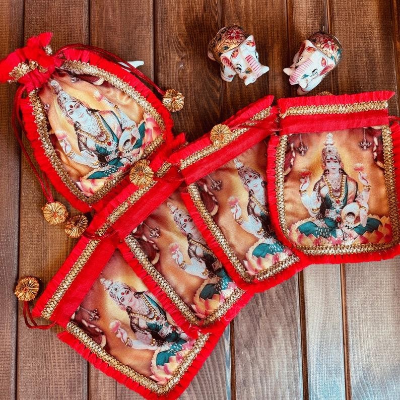 K&ouml;nnte beinhalten: Satz mit sechs roten Samt-Zugbeuteln mit goldenen Verzierungen. Jeder Beutel zeigt ein gedrucktes Bild einer hinduistischen Gottheit, Lakshmi, in sitzender Pose. Die Beutel sind mit goldenen Quasten verziert.