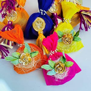 May include: Assortment of colorful fabric pouches with gold accents and decorative embellishments. The pouches are filled with dried herbs and flowers.