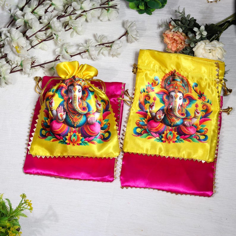 K&ouml;nnte beinhalten: Zwei gelbe Satin-Kordelbeutel mit rosa Satin-Futter. Jeder Beutel zeigt eine farbenfrohe Illustration der hinduistischen Gottheit Ganesha.