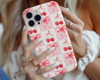 May include: A pink and white phone case with a pattern of cherries and bows. The case is designed for an iPhone.