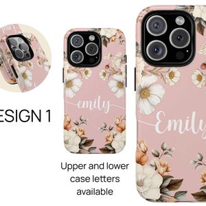 May include: A pink phone case with a floral design and the name "Emily" written in white. The case has a white background with pink flowers and green leaves. The name "Emily" is written in a cursive font.