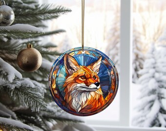 May include: A round Christmas ornament featuring a stained glass style fox with orange, red, yellow, blue, and green colors. The fox is looking to the right and has a white background.