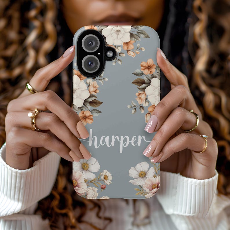 May include: A light blue phone case with a floral design and the name "harper" printed in white.