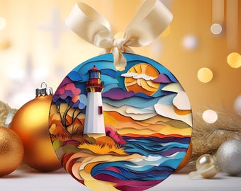 Könnte beinhalten: Runder Weihnachtsschmuck mit einer Leuchtturmszene. Der weiße Leuchtturm steht vor blauem Himmel und einem farbenfrohen Sonnenuntergang. Der Schmuck hat ein cremefarbenes Band und ist von anderen goldenen und silbernen Kugeln umgeben.