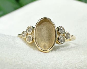 Op de afbeelding: Een gouden ring met een ovale zetting en vijf kleine ronde diamanten. De ring ligt op een witte achtergrond.