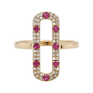 May include: A gold ring featuring an elongated oval design. The oval is outlined with small white diamonds and accented with vibrant red gemstones. The ring's band is a simple, polished gold.