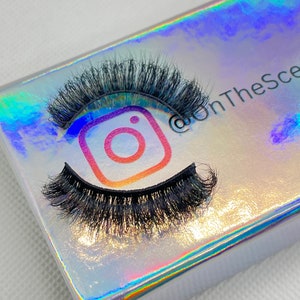 May include: A pair of black false eyelashes in a holographic box with the Instagram logo and the text "@OnTheSce" on the box.