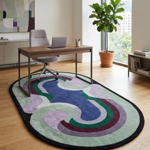 Puede incluir: Una alfombra ovalada con borde negro y dise&ntilde;o abstracto colorido. La alfombra presenta tonos de azul, verde, morado y burdeos. Se encuentra debajo de un escritorio de madera con un port&aacute;til y una silla de oficina gris.