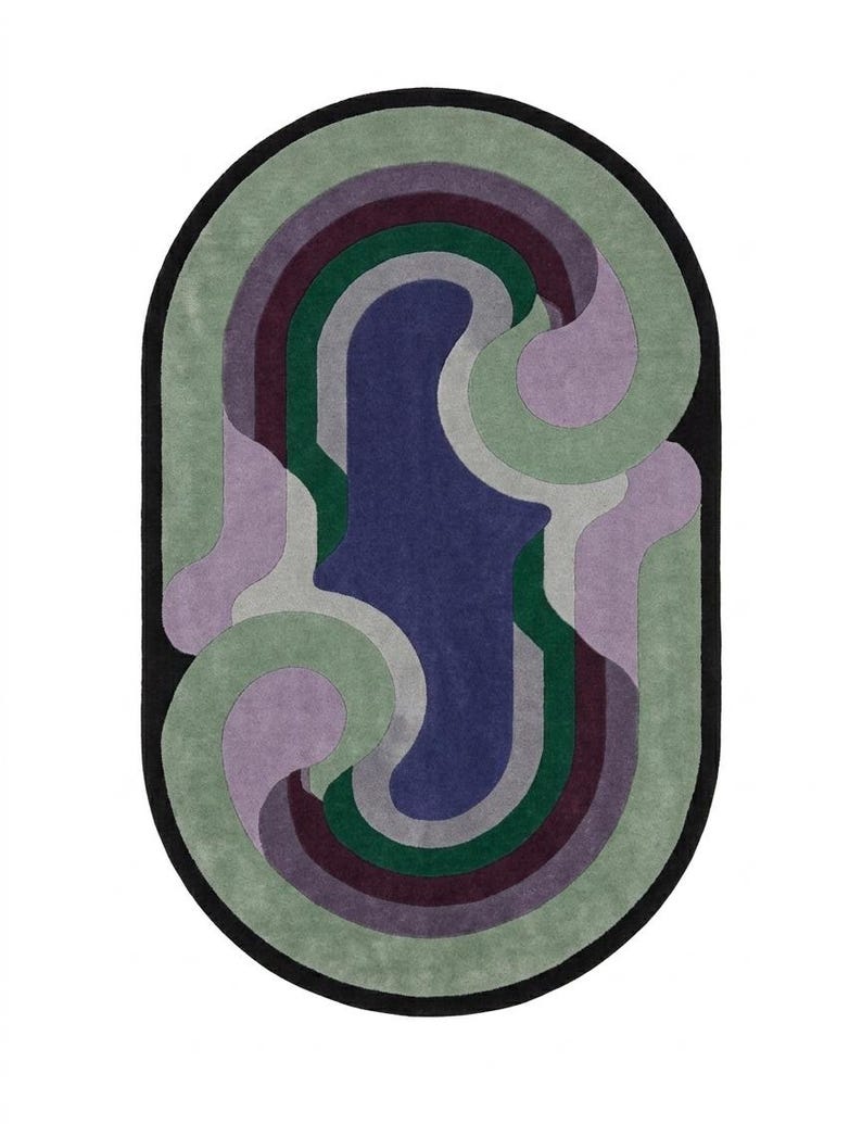 Puede incluir: Alfombra ovalada con borde negro y dise&ntilde;o abstracto. El dise&ntilde;o incluye formas curvas en tonos verdes, morados, grises y burdeos, con una zona central azul. Dise&ntilde;o moderno y art&iacute;stico.
