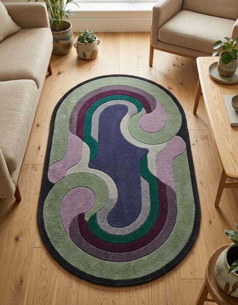 Puede incluir: Alfombra ovalada con un dise&ntilde;o abstracto en tonos verdes, morados y azules. La alfombra tiene un borde gris oscuro y est&aacute; colocada sobre un suelo de madera clara. El dise&ntilde;o presenta l&iacute;neas y formas curvas. La habitaci&oacute;n tambi&eacute;n contiene muebles y plantas en macetas.