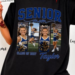 Op de afbeelding: Een zwart t-shirt met de tekst SENIOR mom in blauwe letters. Onder de tekst staan drie fotopanelen van een cheerleader in een blauw en goud uniform. Het shirt bevat de tekst Class of 2027 en Taylor in blauw handschrift.