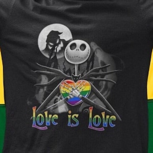 May include: A black t-shirt with a graphic of Jack Skellington from The Nightmare Before Christmas holding a rainbow heart. The text "Love is Love" is printed below the graphic. The person wearing the shirt is standing in front of a rainbow pride flag.