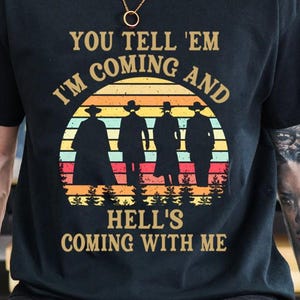 May include: Black t-shirt with a graphic design featuring four silhouetted figures in hats against a sunset backdrop. The text reads "YOU TELL 'EM I'M COMING AND HELL'S COMING WITH ME."