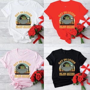May include: Four t-shirts in white, red, pink, and black, each featuring a graphic of a character in a pod with the text "GET IN LOSER WE ARE GETTING CHICKY NUGGIES". Each shirt is paired with a bouquet of red roses and a gift.