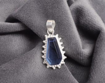 May include: A silver pendant with a dark blue gemstone set in a decorative silver frame.