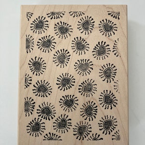 May include: A wooden stamp with a repeating pattern of black hearts with a sunburst design around them.