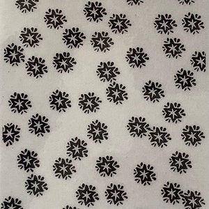May include: A white background with a repeating pattern of black star-shaped designs.