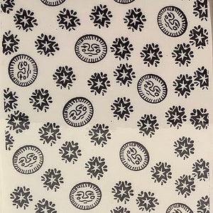 May include: A white background with a repeating pattern of black stars and black circles with a face inside.