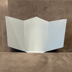 Pu&ograve; includere: Un design in carta piegata, geometrico, stampato in 3D, di colore bianco. Il design ha la forma di una stella a cinque punte.