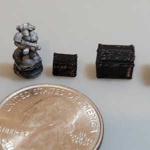 Puede incluir: Una figurita miniatura pintada de gris de un marine espacial sosteniendo un arma, junto a cuatro cofres de madera negra en miniatura de diferentes tama&ntilde;os. Se incluye una moneda de 25 centavos de d&oacute;lar estadounidense para la escala.