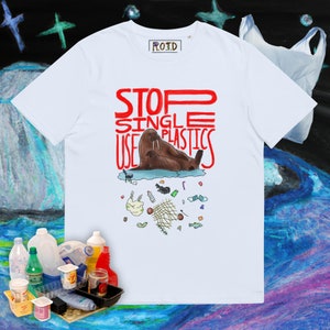 May include: White t-shirt with a red graphic that says "STOP SINGLE USE PLASTICS". The graphic also features a cartoon walrus and a pile of plastic trash.