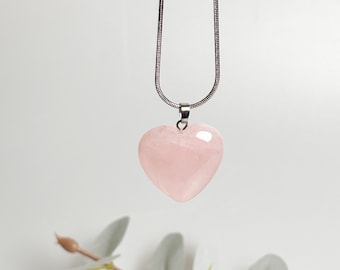 May include: A silver chain necklace with a light pink heart-shaped pendant.