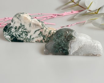 May include: Two green, white, and gray agate cloud-shaped stones. The stones are polished and have a natural, organic look.