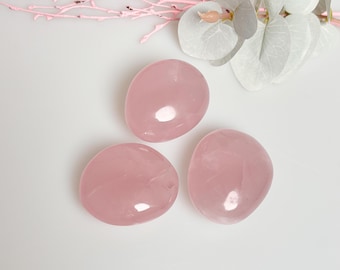 May include: Three smooth, heart-shaped rose quartz stones in various sizes. The stones are a pale pink color and have a glossy finish.